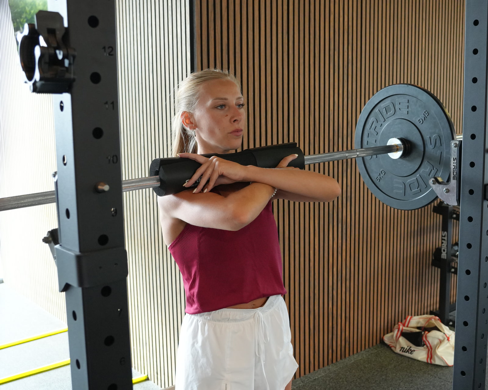 Atlete met de halterstang op de schouders in het rek.